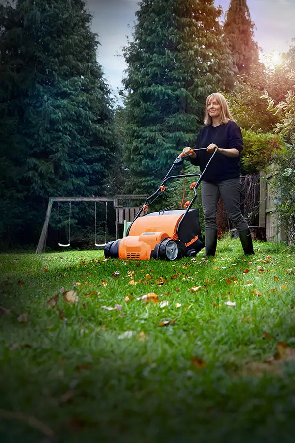Woman with LawnMaster Scarifier removing tatch and moss from UK lawn