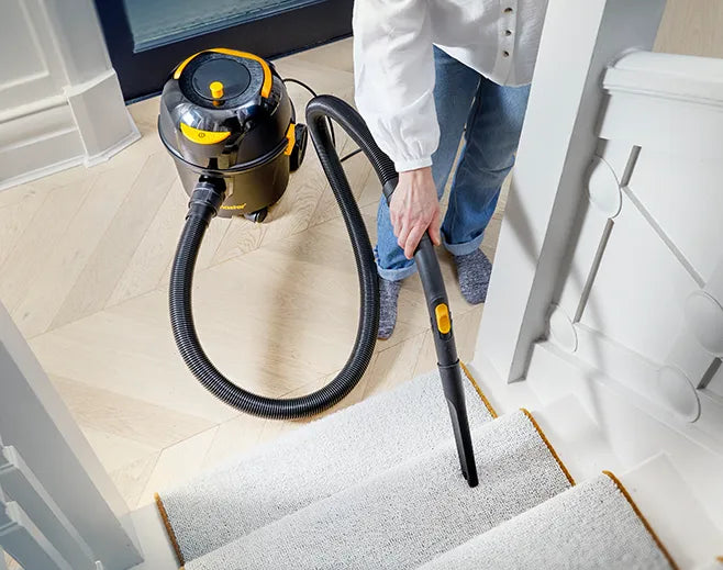 person vacuuming stairs easily with Vacmaster D8's long cable