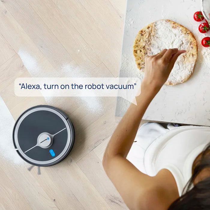Robot vacuum cleaner Vacmaster REi vacuuming in front of sofa with woman and dog