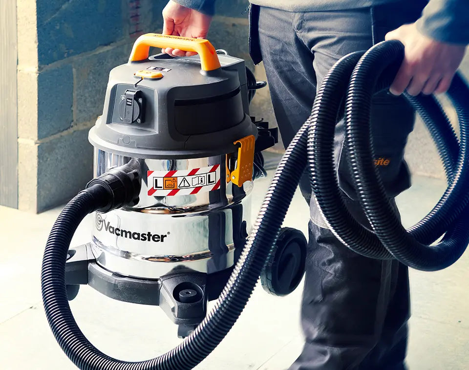 l class vacmaster 20 litre dust extractor being carried across building site