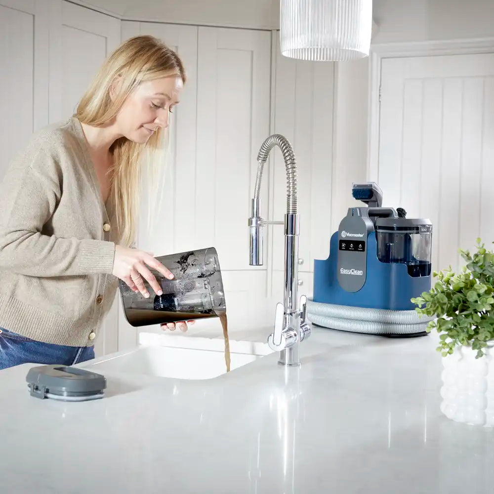 Vacmaster EasyClean Thermo heated spot cleaner being emptied of dirty water down kitchen sink