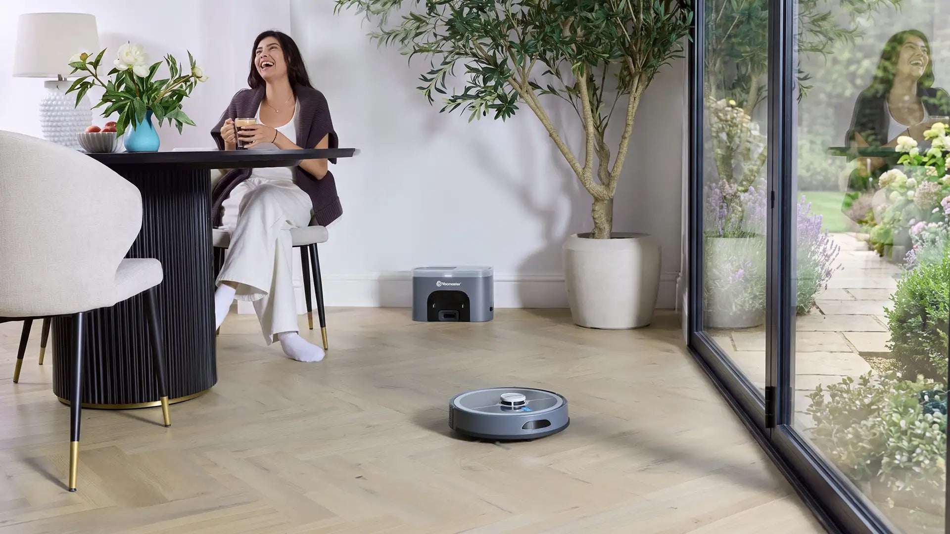 Vacmaster REi Robot Vacuum Cleaner with Self-Empty Station in open plan kitchen with woman relaxing 