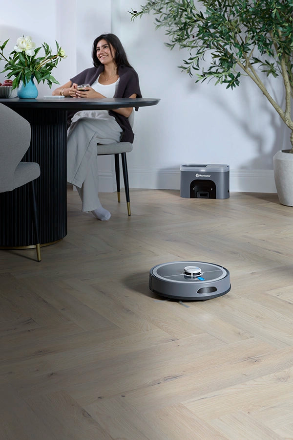 Vacmaster REi Robot Vacuum Cleaner with Self-Empty Station in open plan kitchen with woman relaxing mob