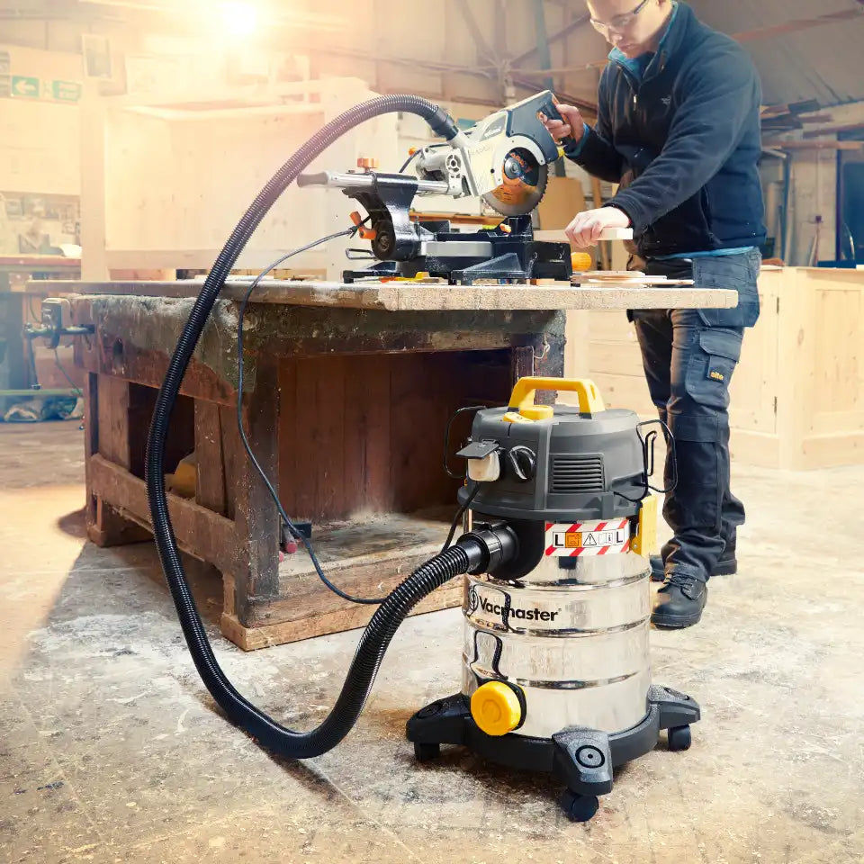 Vacmaster 30L Wet and Dry Dust Extractor being used by tradesman in factory setting using Power Take Off socket